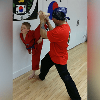 A man and boy practicing martial arts in the room.