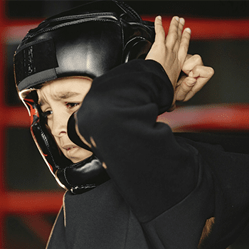 A man wearing a black helmet and holding his hand up to the side of his head.