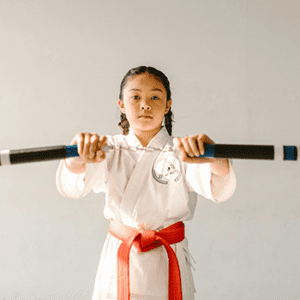 A young girl holding two wooden sticks in her hands.