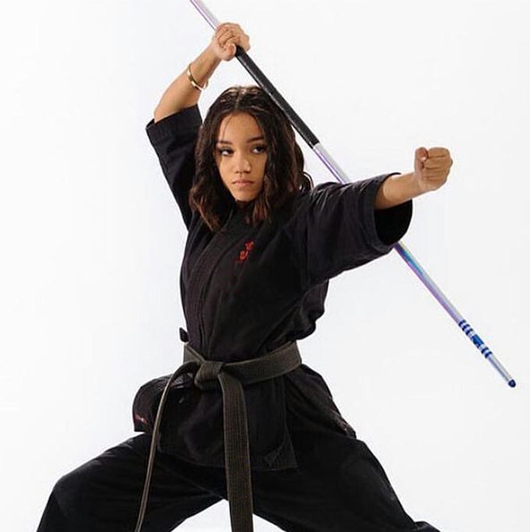 A woman in black shirt holding two sticks.